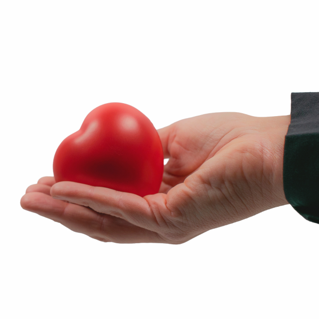 Mjuk röd hjärtformad stressboll visas i en öppen hand, perfekt för avkoppling.