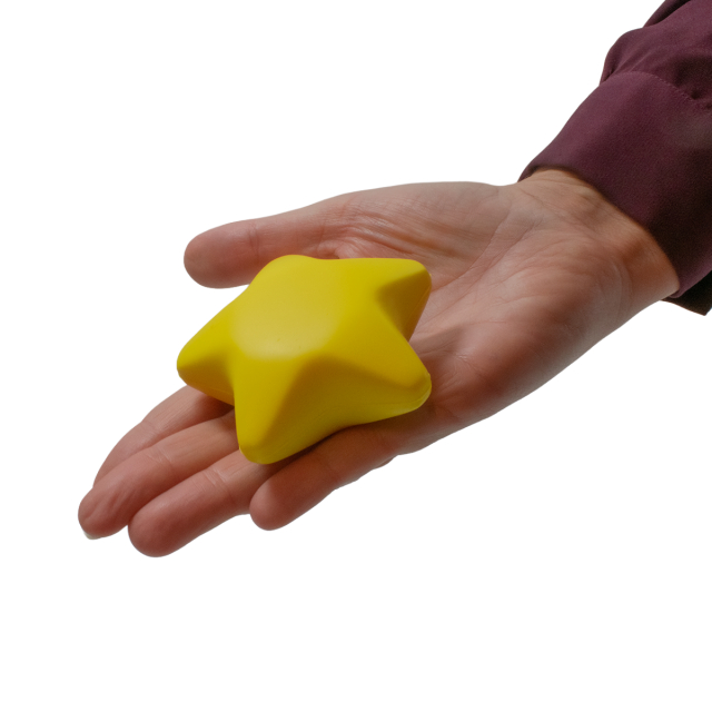 Mjuk gul stjärnformad stressboll ligger i en öppen hand, redo att klämmas.