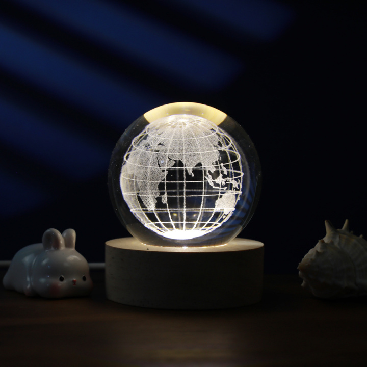 Kristallkula med världskarta och varmt ljus från träsockel